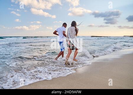 Glückliches Paar, das am Sommertag am Strand zusammen läuft, Rückansicht Stockfoto