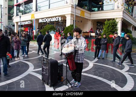 Street Drummer auf dem zentralen Platz von Baku - Aserbaidschan: 31. Dezember 2021. Ein Straßenmusiker spielt tom-tom auf einer Trommel. Stockfoto