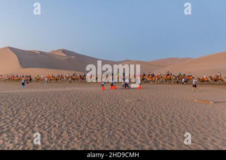 DUNHUANG, CHINA - 21. AUGUST 2018: Kamelsafari in der Singing Sands Dune in der Nähe von Dunhuang, Provinz Gansu, China Stockfoto