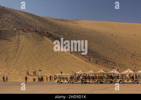 DUNHUANG, CHINA - 21. AUGUST 2018: Touristen klettern auf die Singende Sanddüne in der Nähe von Dunhuang, Provinz Gansu, China Stockfoto