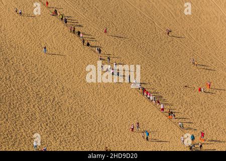 DUNHUANG, CHINA - 21. AUGUST 2018: Touristen klettern auf die Singende Sanddüne in der Nähe von Dunhuang, Provinz Gansu, China Stockfoto