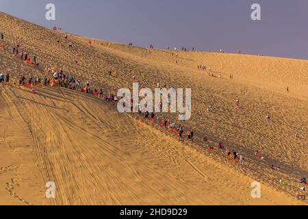 DUNHUANG, CHINA - 21. AUGUST 2018: Touristen klettern auf die Singende Sanddüne in der Nähe von Dunhuang, Provinz Gansu, China Stockfoto