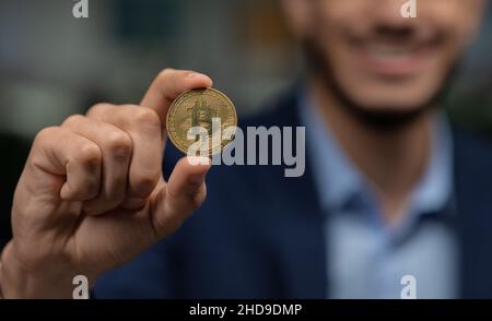 Digitale Währung. Arabischer Geschäftsmann mit goldenem Bitcoin, Nahaufnahme der Hand Stockfoto