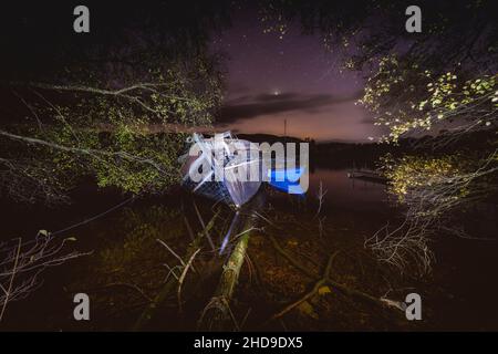 Die alten, verfallenden Boote vertäuten in einer sehr, sehr dunklen Novembernacht am Ufer des Loch Ness in der Nähe von Fort Augustus. Es gibt etwas sehr Unsettlin Stockfoto