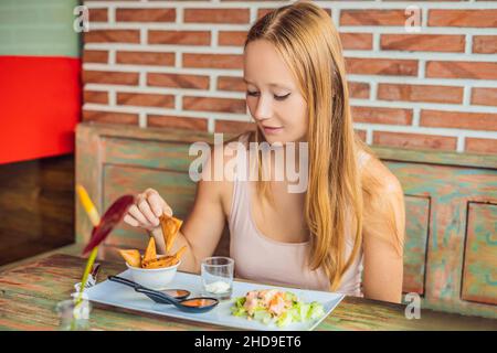 Frau, die im Café isst. Lifestyle. Das Gericht besteht aus Salat, Samosa und verschiedenen Saucen Stockfoto