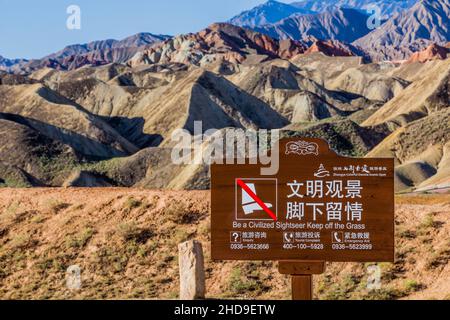 ZHANGYE, CHINA - 23. AUGUST 2018: Zeichen Sie ein zivilisierter Seher Halten Sie sich vom Gras im nationalen Geopark Zhangye Danxia, Provinz Gansu, China Stockfoto