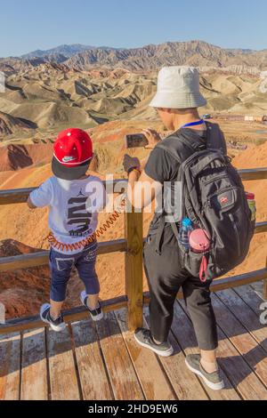 ZHANGYE, CHINA - 23. AUGUST 2018: Vater mit Kind im Nationalen Geopark Zhangye Danxia, Provinz Gansu, China Stockfoto