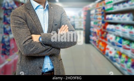 Geschäftsmann vor verschwommenem Supermarktgang Stockfoto