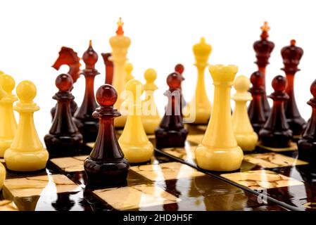Naturbernsteinfarben verschiedene Schachfiguren stehen auf Perlentafel in Weiß. Nahaufnahme Spiel Konzept Wettbewerb, Classic Turnier der Konfrontation. Stockfoto