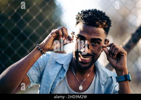Porträt eines afroamerikanischen Mannes, der über seiner Brille lächelnd auf die Kamera blickt Stockfoto
