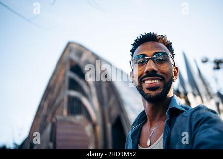 Ein junger afroamerikanischer Mann, der lächelnd ein Selfie auf der Straße nimmt Stockfoto