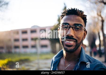 Porträt eines jungen lächelnden Afro-Mannes auf der Straße (Nahaufnahme) Stockfoto
