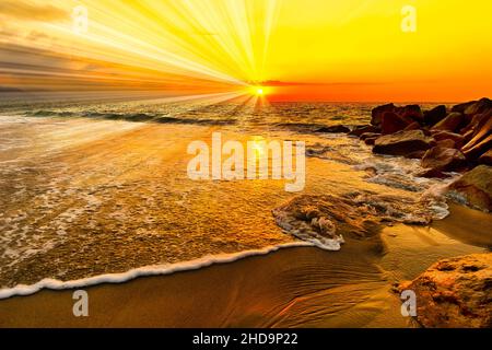 Ein farbenfroher Sonnenuntergang im Ozean mit Sonnenstrahlen, die über dem Ocean Horizon ausstrahlen Stockfoto