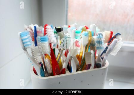 Eine Auswahl an bunten Zahnbürsten aus Kunststoff in einem Topf in einem Badezimmer in Chichester, West Sussex, Großbritannien. Stockfoto