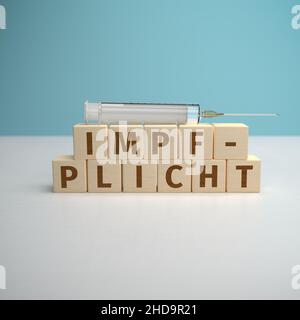 Das deutsche Wort Impfpflicht wurde aus Buchstaben auf Holzwürfeln gebaut. Stockfoto