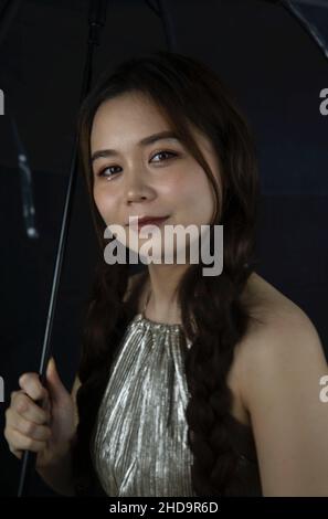 Porträt einer lächelnden schönen jungen Frau aus Vietnam mit einem Regenschirm Stockfoto