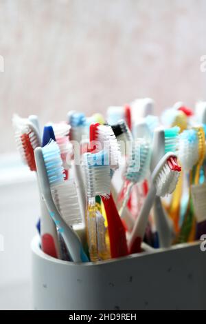 Eine Auswahl an bunten Zahnbürsten aus Kunststoff in einem Topf in einem Badezimmer in Chichester, West Sussex, Großbritannien. Stockfoto