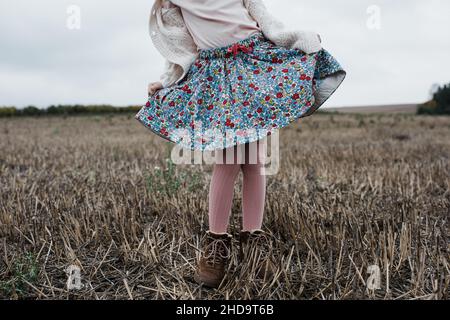 Mädchen, die ein Curtsy beim Spielen draußen auf einem Feld Stockfoto