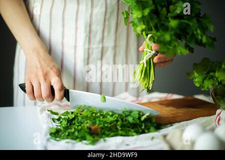 Anonyme Frau hackt Petersilie / Koriander Stockfoto