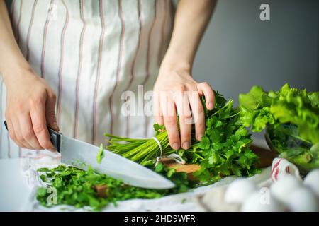 Anonyme Frau hackt Petersilie / Koriander Stockfoto