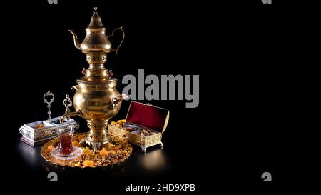 Orientalischer Tee in einem Samowar, mit Süßigkeiten auf schwarzem Hintergrund Stockfoto