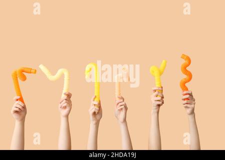 Hände mit beliebten Pop-Tubes auf farbigem Hintergrund Stockfoto