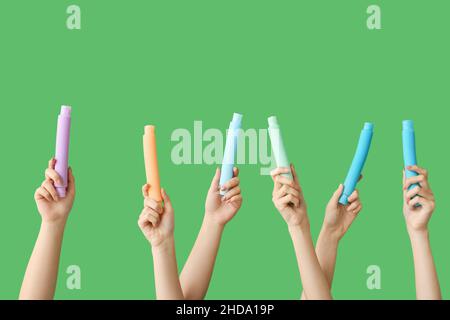 Hände mit beliebten Pop-Tubes auf farbigem Hintergrund Stockfoto