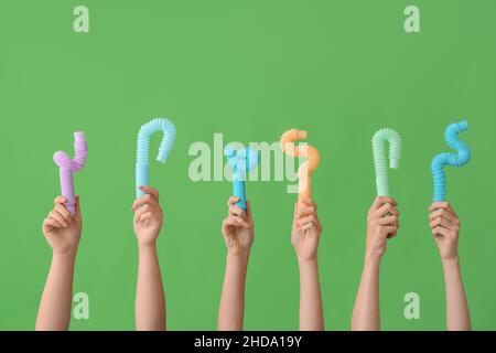 Hände mit beliebten Pop-Tubes auf farbigem Hintergrund Stockfoto