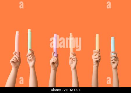 Hände mit beliebten Pop-Tubes auf farbigem Hintergrund Stockfoto