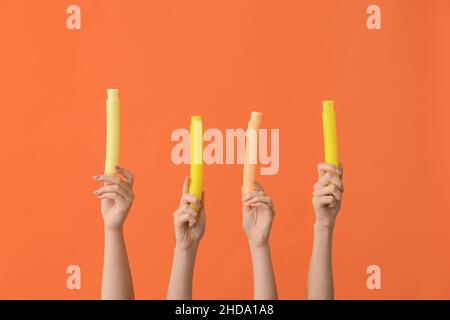 Hände mit beliebten Pop-Tubes auf farbigem Hintergrund Stockfoto