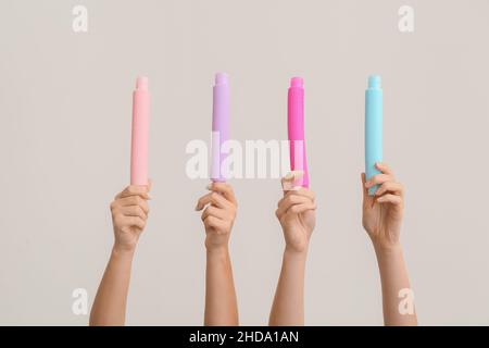 Hände mit beliebten Pop-Tubes auf hellem Hintergrund Stockfoto