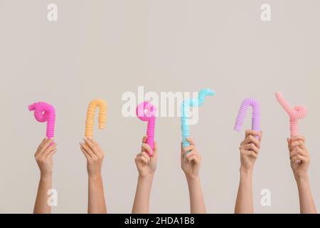 Hände mit beliebten Pop-Tubes auf hellem Hintergrund Stockfoto