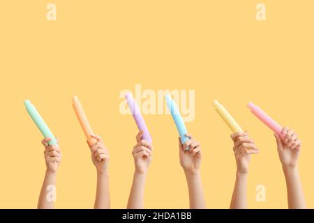 Hände mit beliebten Pop-Tubes auf farbigem Hintergrund Stockfoto