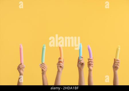 Hände mit beliebten Pop-Tubes auf farbigem Hintergrund Stockfoto