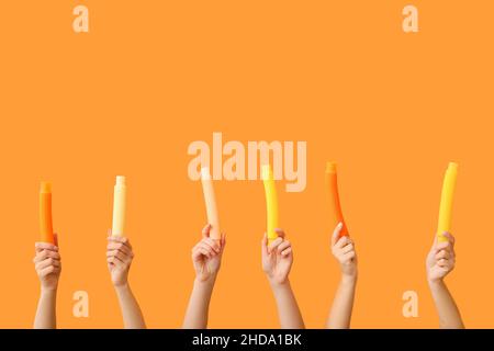Hände mit beliebten Pop-Tubes auf farbigem Hintergrund Stockfoto