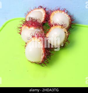 Nahaufnahme eines geöffneten Rambutans auf einem grünen Hintergrund Stockfoto