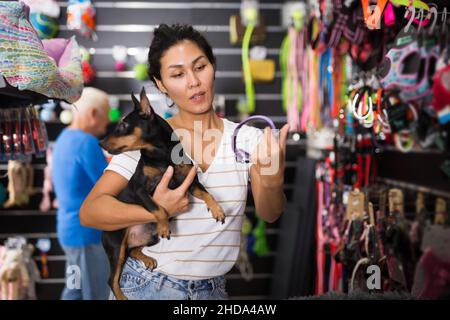 Asiatische Frau mit Hund Auswahl Kragen im Tiergeschäft Stockfoto