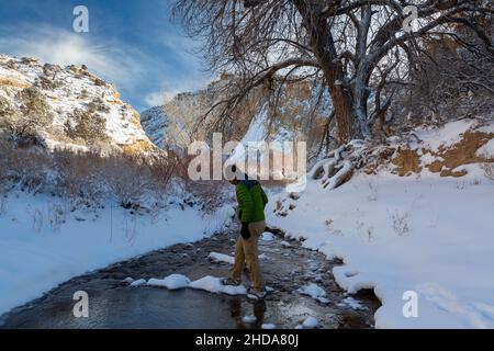 Ein männlicher Wanderer testete einen möglichen Halt im Escalante River, nachdem die Landschaft von Schnee bedeckt war. Grand Staircase-Escalante National Monumen Stockfoto