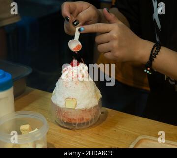 Draufsicht auf Bingsu oder koreanisches rasierte Eisdessert mit Kirschsahne und gesüßter Kondensmilch, Fokus selektiv. Stockfoto