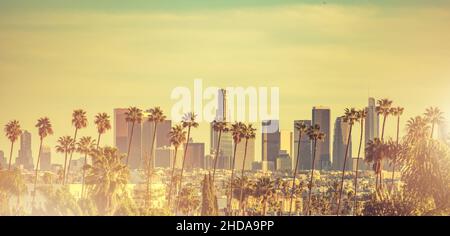 Los Angeles liegt in einem Becken in Südkalifornien, angrenzend an den Pazifischen Ozean. Downtown Towers und The Palms. Warme Farbsortierung bei Sonnenuntergang und Panora Stockfoto