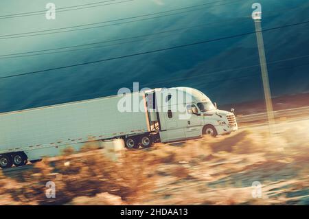 Speeding Modern Semi Trailer Truck auf einem Desert Highway in Südkalifornien. Trucking-Thema. Stockfoto