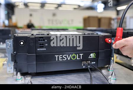 PRODUKTION - 18. November 2021, Sachsen-Anhalt, Wittenberg: Ein Mitarbeiter der Tesvolt GmbH beginnt mit der Zyklisierung der Batterien in der Qualitätssicherung. TESVOLT entwickelt und baut Batteriespeichersysteme für Handel und Industrie. Die Lithium-Energiespeicher auf Basis von Nickel-Mangan-Kobalt-Oxid können mit allen regenerativen Energiequellen kombiniert werden, einschließlich eines Blockheizkraftwerks oder einer Brennstoffzelle. Nach eigenen Angaben hat das Unternehmen weltweit bereits mehr als 2200 Speicherprojekte realisiert. (Um dpa 'Wittenberg Technologieunternehmen erweitert - Staat konzentriert sich auf Energie s Stockfoto