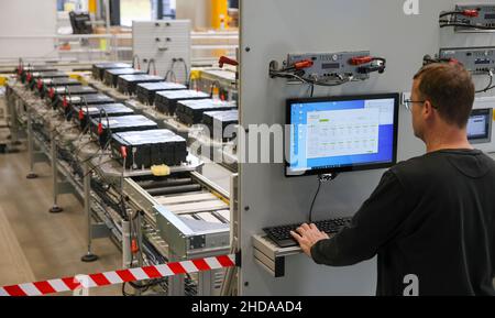 PRODUKTION - 18. November 2021, Sachsen-Anhalt, Wittenberg: Ein Mitarbeiter der Tesvolt GmbH überwacht die Zyklisierung der Batterien in der Qualitätssicherung. TESVOLT entwickelt und baut Batteriespeichersysteme für Handel und Industrie. Die Lithium-Energiespeicher auf Basis von Nickel-Mangan-Kobalt-Oxid können mit allen regenerativen Energiequellen kombiniert werden, einschließlich eines Blockheizkraftwerks oder einer Brennstoffzelle. Nach eigenen Angaben hat das Unternehmen weltweit bereits mehr als 2200 Speicherprojekte realisiert. (To dpa 'Wittenberg Technologieunternehmen expandiert - Staat konzentriert sich auf Energie sto Stockfoto