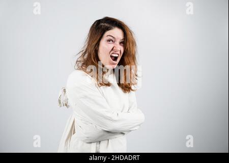 Nahaufnahme Porträt einer verrückten Frau in Zwangsjacke auf weißem Hintergrund. Stockfoto