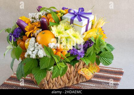 Korb mit frischem Obst, Gemüse und Blumen auf hellem Hintergrund Stockfoto