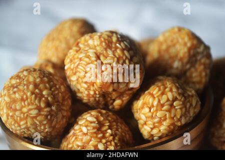 Nahaufnahme eines gezackelten Sesams/Til Laddu/Laddoo in einem Messinggerät/urli/Makar Sankranti/Indien Stockfoto