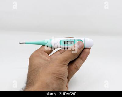 Eine Nahaufnahme des niedrigen Messwerts in einem Digitalthermometer in den Händen einer Person, die auf weißem Hintergrund isoliert ist Stockfoto