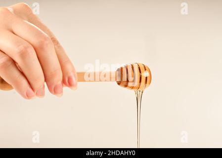 Dipper mit Honig in Frauenhand. Platz für Text oder Design. Stockfoto
