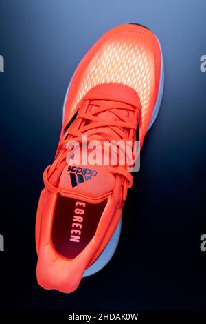 Tjumen, Russland-13. November 2021: Neue Adidas-Sneaker in orange Farbe. Das Modell besteht aus recycelten Materialien. Vertikales Foto Stockfoto