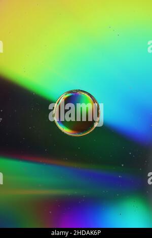 Nahaufnahme eines schönen Öltropfens auf einer hell erleuchteten Wasseroberfläche Stockfoto